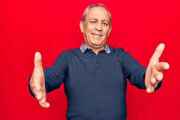 Sticker - Senior man with grey hair wearing casual polo looking at the camera smiling with open arms for hug. cheerful expression embracing happiness.