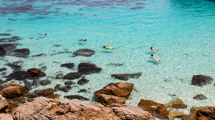 Snorkelling people in turquoise water on tropical Malaysian island Perhentian Besar