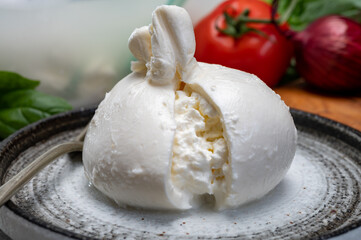 Eating of fresh handmade soft Italian cheese from Puglia, white balls of burrata or burratina cheese made from mozzarella and cream filling