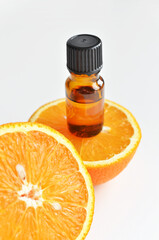 Orange citrus essential oil in dark glass bottle with fresh orange fruit halves. Aromatherapy treatment.