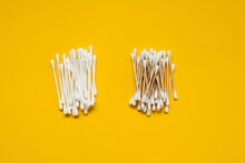 Plastic Vs Organic Wooden Cotton Swabs On A Bright Yellow Background. Concept Of Taking Care Of The Environment.