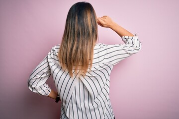 Poster - Young beautiful woman wearing casual striped t-shirt and glasses over pink background Backwards thinking about doubt with hand on head