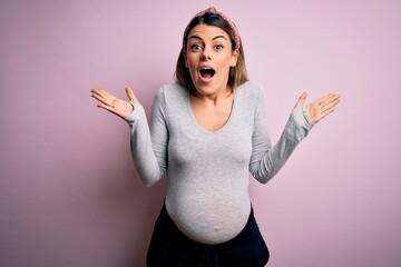 Sticker - Young beautiful brunette woman pregnant expecting baby over isolated pink background celebrating crazy and amazed for success with arms raised and open eyes screaming excited. Winner concept