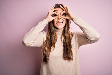 Sticker - Young beautiful girl wearing casual turtleneck sweater standing over isolated pink background doing ok gesture like binoculars sticking tongue out, eyes looking through fingers. Crazy expression.