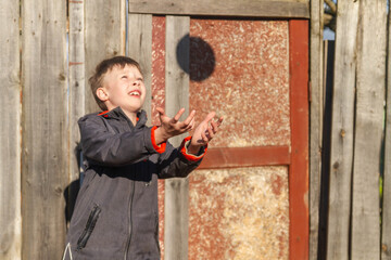 A 10-year-old European boy catches a ball in the street.