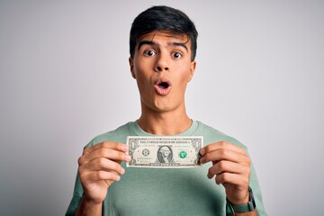 Poster - Young handsome man holding one dollar banknotes over isolated white background scared in shock with a surprise face, afraid and excited with fear expression