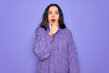 Wall Mural - Young beautiful woman wearing casual turtleneck sweater standing over purple background Looking fascinated with disbelief, surprise and amazed expression with hands on chin