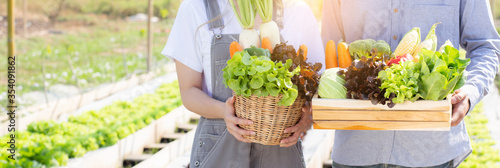 Fotomural Beautiful young asian woman and man harvest and picking up fresh organic vegetable garden in basket at hydroponic farm, agriculture for healthy food and business entrepreneur concept, banner website
