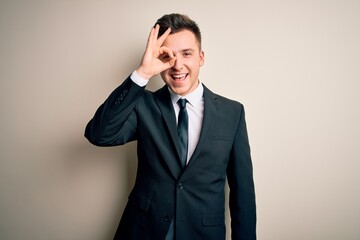 Wall Mural - Young handsome business man wearing elegant suit and tie over isolated background doing ok gesture with hand smiling, eye looking through fingers with happy face.