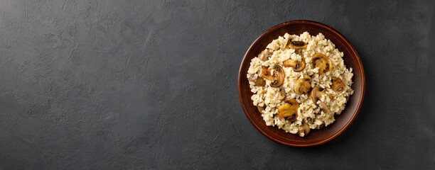 Traditional italian cuisine meal - vegetarian risotto with mushrooms. Black stone backround. Restaurant or cafe menu concept. Long banner format.