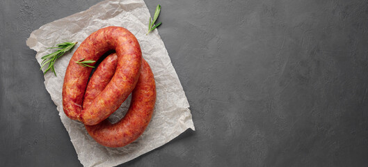 Wall Mural - Smoked sausage with rosemary on a gray slate background. Copy space for text.