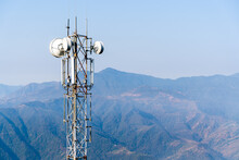 Telecommunication Tower With Antennas. Wireless Communication Antenna Transmitter With Mountains On Background. Stock Photo.