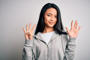 Wall Mural - Young beautiful chinese sporty woman wearing sweatshirt over isolated white background showing and pointing up with fingers number nine while smiling confident and happy.