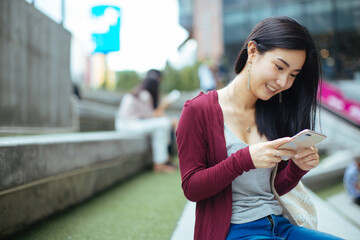 Young woman using smart phone on a city street.