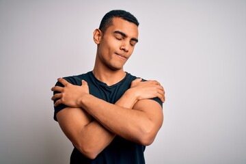 Young handsome african american man wearing casual t-shirt standing over white background Hugging oneself happy and positive, smiling confident. Self love and self care