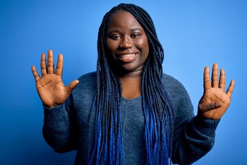 Sticker - African american plus size woman with braids wearing casual sweater over blue background showing and pointing up with fingers number nine while smiling confident and happy.