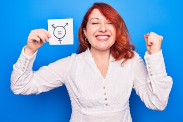 Wall Mural - Redhead woman asking for sex discrimination holding paper with transgender equality message screaming proud, celebrating victory and success very excited with raised arm