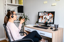 Young Successful Employee Is Have A Meeting With Her Team Using A Headset, She Is Sitting Relaxed And Smiling, A Middle Side Shot.