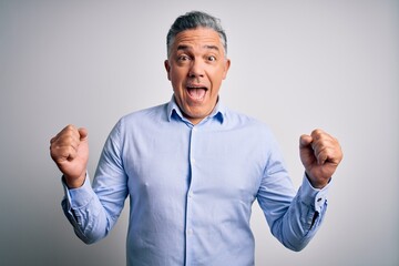 Sticker - Middle age handsome grey-haired business man wearing elegant shirt over white background celebrating surprised and amazed for success with arms raised and open eyes. Winner concept.