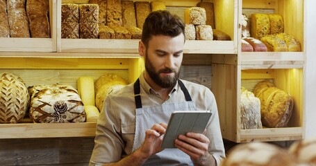 Portrait of male baker working in bakery shop and using tablet