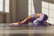 Yoga girl. Attractive sporty woman practices yoga. Relaxes. Meditates in a sunny room in the morning at sunrise.
