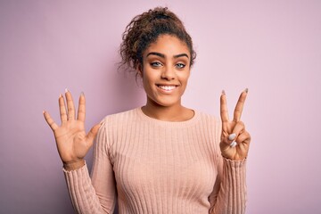 Canvas Print - Young beautiful african american girl wearing casual sweater standing over pink background showing and pointing up with fingers number seven while smiling confident and happy.