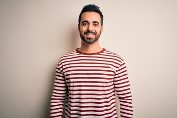 Sticker - Young handsome man with beard wearing casual striped t-shirt standing over white background with a happy and cool smile on face. Lucky person.