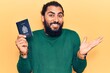 Young arab man holding canada passport celebrating achievement with happy smile and winner expression with raised hand