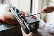 © Zoran - The gunsmith adjusts the optical sight of the sport air rifle. Adjusting the sniper rifle at a distance