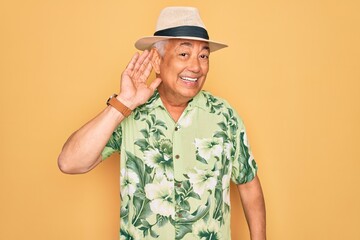 Canvas Print - Middle age senior grey-haired man wearing summer hat and floral shirt on beach vacation smiling with hand over ear listening an hearing to rumor or gossip. Deafness concept.