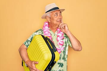 Sticker - Middle age senior grey-haired man on holiday holding vacation suitcase over yellow background serious face thinking about question, very confused idea