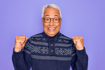 Wall Mural - Middle age senior grey-haired man wearing glasses and winter sweater over purple background celebrating surprised and amazed for success with arms raised and open eyes. Winner concept.