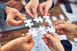 © Krakenimages.com - Group of business workers with hands together connecting pieces of puzzle at the office