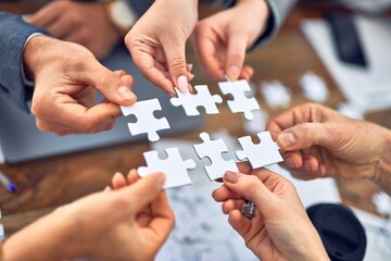 Group of business workers with hands together connecting pieces of puzzle at the office