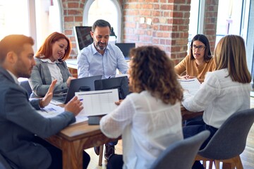 Poster - Group of business workers working together. Sitting on desk using laptop reading documents at the office