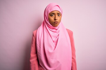 Wall Mural - Young African American afro woman wearing muslim hijab over isolated pink background depressed and worry for distress, crying angry and afraid. Sad expression.