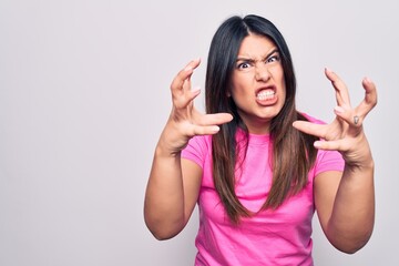 Canvas Print - Young beautiful brunette woman wearing casual pink t-shirt standing over white background Shouting frustrated with rage, hands trying to strangle, yelling mad