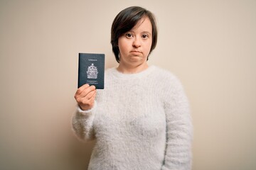 Canvas Print - Young down syndrome tourist woman holding canada passport as trip document with a confident expression on smart face thinking serious