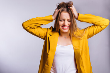 Wall Mural - young woman in a yellow trouser suit hold hands in her hair and