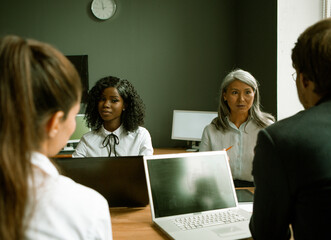 Multi ethnic group of office workers working in unity. Creative busines people discuss ideas of developing a new business project while sitting at same office table.