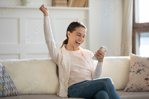 Cuadros en Lienzo Overjoyed young Caucasian woman sit on sofa at home triumph get pleasant unexpec