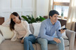 © fizkes - Unhappy mad young woman sit separately angry at smiling man spouse watching football match on TV, millennial caucasian couple disagreement misunderstanding on television program or channel choice