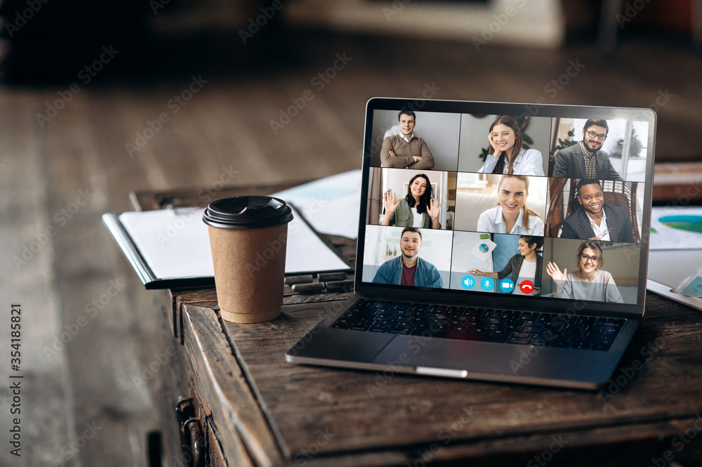 Virtual meeting online. Video conference by laptop. Online business meeting. On the laptop screen, people who gathered in a video conference to work on-line, near stands a cup of coffee - obrazy, fototapety, plakaty 
