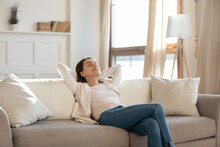 Relaxed happy young woman relax on comfortable couch at home sleeping or taking nap, smiling millennial girl rest on sofa at home, enjoy sunny weekend, breathe fresh air, stress free concept