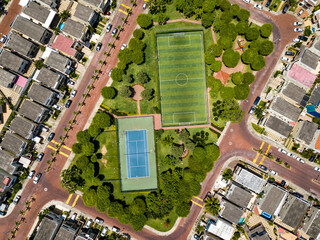 Straight down drone shot of empty mini soccer field and tenis court surrounded by park and trees in a gated community outside Guayaquil City, Ecuador.