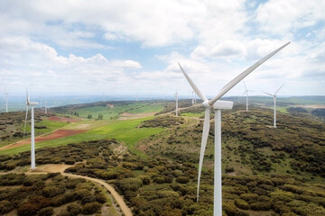 Aerial view of windmills farm for clean energy production on beautiful cloudy sky. Wind power turbines generating clean renewable energy for sustainable development .