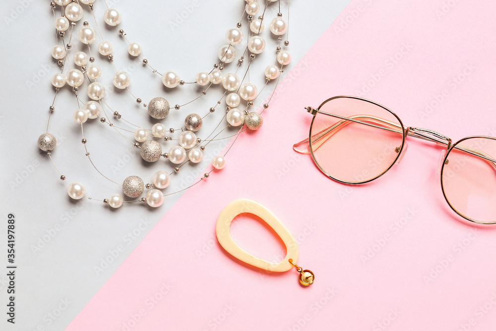 Beautiful jewelry with eyeglasses on color background