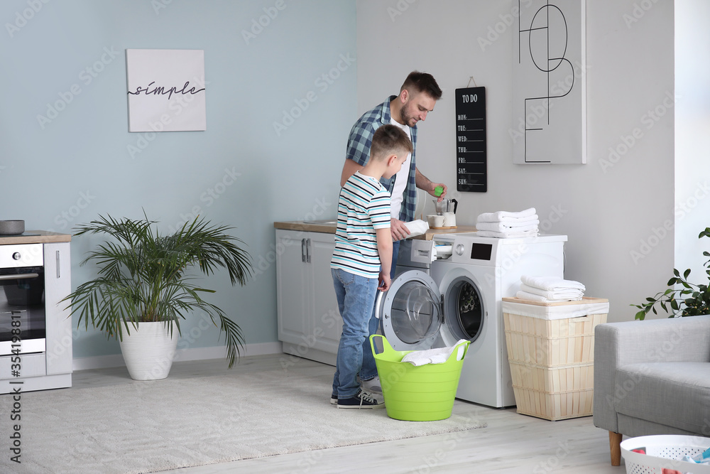 Man and his little son doing laundry at home