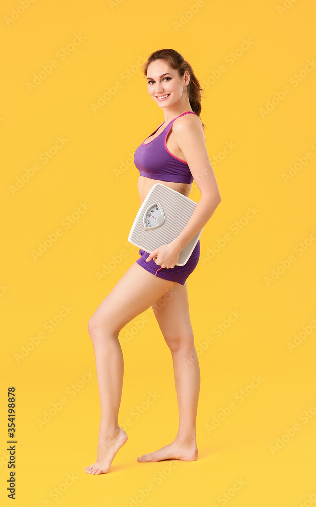 Young woman with weight scales on color background