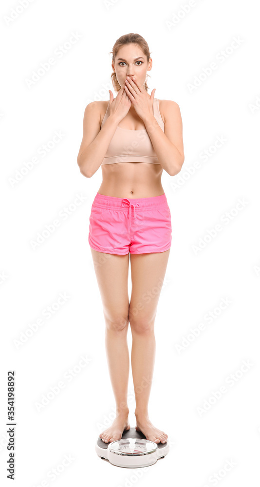 Shocked young woman measuring her weight on white background
